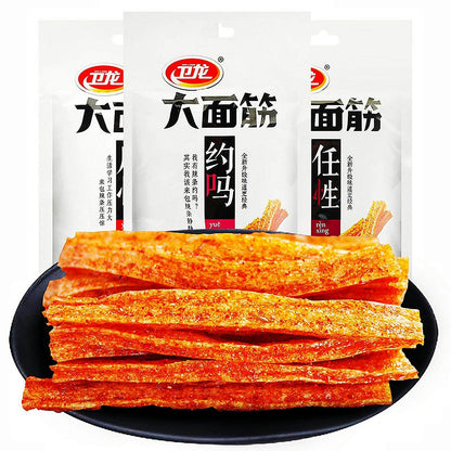 Chinese Spicy Latiao Gluten Strips in a black bowl with packaging in the background. Viral TikTok Chinese Latiao